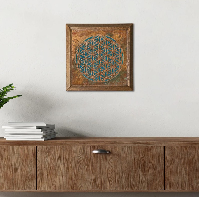 May include: Square wall art featuring a geometric flower of life design. The artwork has a teal and gold color scheme, with a wooden frame. The flower of life is a sacred geometry symbol.