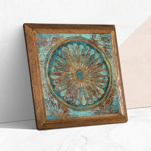K&ouml;nnte beinhalten: Quadratische Holzrahmen-Kunst mit einem t&uuml;rkis-goldenen Blumendesign. Das Kunstwerk hat ein verwittertes, strukturiertes Aussehen. Der Rahmen besteht aus Naturholz. Das Kunstwerk lehnt an einer wei&szlig;en Wand.