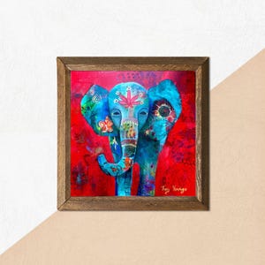Puede incluir: Obra de arte enmarcada que presenta un elefante azul estilizado sobre un fondo rojo. El elefante est&aacute; adornado con patrones florales y geom&eacute;tricos en varios colores. La obra est&aacute; firmada por la artista, Tracy Verchage.