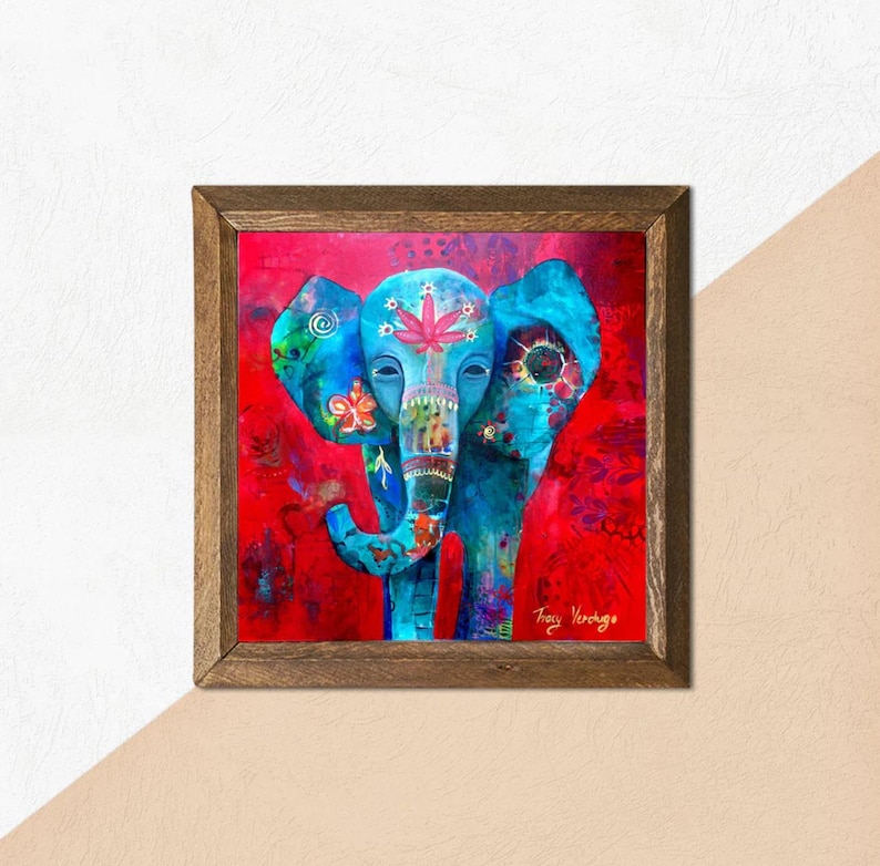 Puede incluir: Obra de arte enmarcada que presenta un elefante azul estilizado sobre un fondo rojo. El elefante est&aacute; adornado con patrones florales y geom&eacute;tricos en varios colores. La obra est&aacute; firmada por la artista, Tracy Verchage.