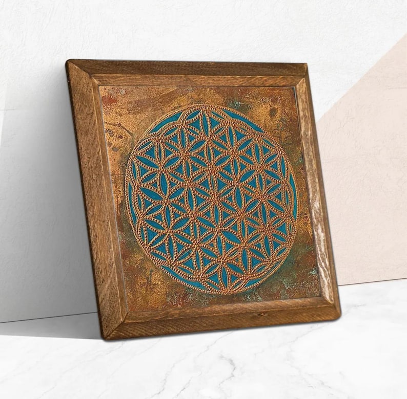 May include: A square wooden wall art piece with a brown frame. The artwork features a teal blue and gold geometric design in the center. The design is a repeating pattern of interconnected circles, creating a symmetrical and visually appealing composition.