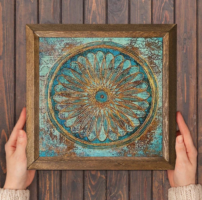 K&ouml;nnte beinhalten: Quadratische gerahmte Kunst mit einem t&uuml;rkis-goldenen Blumendesign. Das Kunstwerk zeigt ein zentrales bl&uuml;tenartiges Motiv mit komplizierten Details und einem strukturierten, verwitterten Hintergrund. Der Rahmen besteht aus Naturholz.