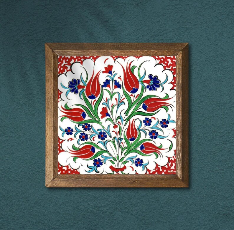 May include: Square framed ceramic tile with a floral design. The tile features red tulips, blue flowers, and green leaves on a white background. The frame is made of wood.