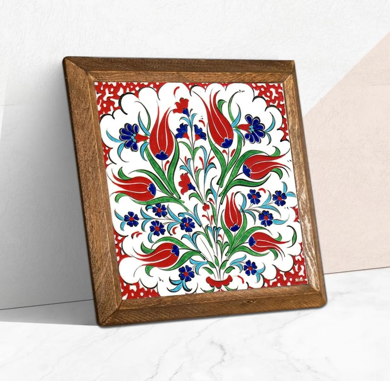 May include: Square framed artwork featuring a floral design with red tulips, blue flowers, and green leaves on a white background. The artwork is framed in a wooden frame.