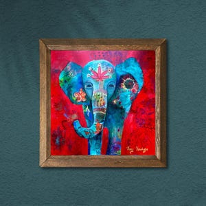 Puede incluir: Obra de arte enmarcada que representa un elefante azul estilizado con motivos florales y de hojas sobre un fondo rojo. La obra tiene un marco de madera. El dise&ntilde;o del elefante incluye una hoja de cannabis.