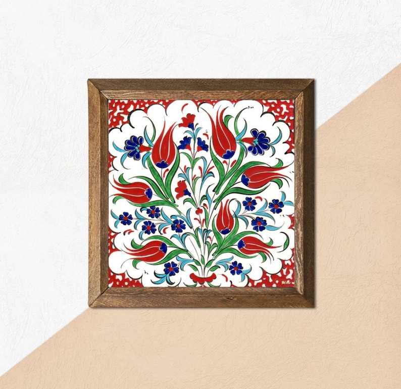 May include: Square framed artwork featuring a floral design. The artwork showcases a white background with a vibrant pattern of red tulips, blue flowers, and green leaves. The frame is made of dark brown wood, adding a classic touch to the piece.