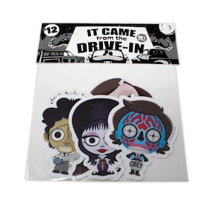 May include: A set of three stickers featuring characters from the horror movie series "It Came from the Drive-In". The stickers are in a clear plastic bag with a black and white header that reads "It Came from the Drive-In Vol. 1".