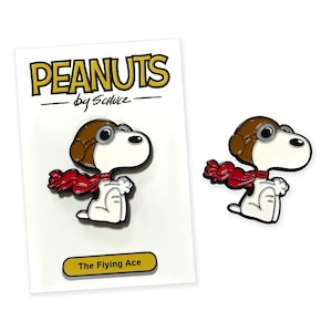May include: Two Snoopy pins, one on a card, featuring Snoopy as The Flying Ace. The pins are white, brown, and red. The card reads "PEANUTS by Schulz" and "The Flying Ace."