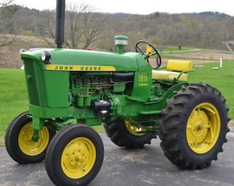 May include: A green John Deere 1010 Diesel tractor with yellow detailing. The tractor features large black tyres with yellow rims, a black exhaust pipe, and the John Deere logo in yellow. The tractor is on grass.
