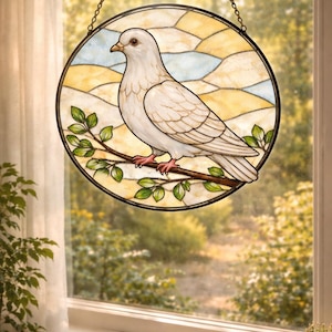 May include: Stained glass window art featuring a white dove perched on a branch with green leaves. The dove is set against a backdrop of yellow, blue, and white stained glass, framed by a black circular border. The window hangs from a chain.