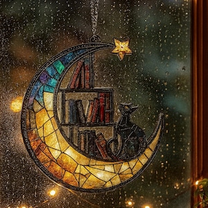 May include: A crescent moon-shaped stained glass suncatcher featuring a multi-colored mosaic pattern, a small bookshelf filled with various books, and a black cat silhouette. A small five-pointed star hangs from the top of the moon frame.