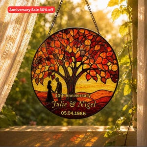 Könnte beinhalten: Ein runder Buntglas-Sonnenfänger mit einem Baum mit orangefarbenen und roten Blättern. Unter dem Baum steht eine Silhouette von zwei Personen in einer Landschaft. Der Text lautet 40th Anniversary, Julie & Nigel und 05.04.1986.