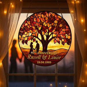May include: A round stained glass window featuring a tree with orange and red leaves. The design includes silhouettes of a couple holding hands, with the text "40th ANNIVERSARY Russell & Louise 19.08.1985".