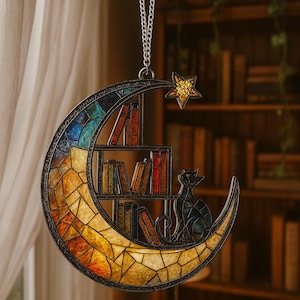 May include: A crescent moon-shaped suncatcher featuring a stained glass mosaic design in shades of blue, orange, and yellow. The piece includes a built-in bookshelf with miniature books and a cat silhouette, topped with a small yellow star.