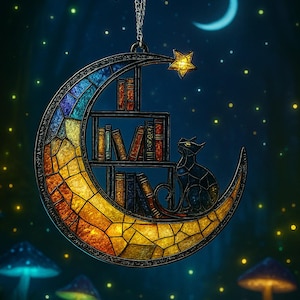May include: A crescent moon-shaped stained glass suncatcher featuring a bookshelf filled with colorful books and a black cat sitting on the lower curve. A small yellow star hangs from the top, and the piece is suspended by a silver chain.