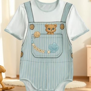 Peut inclure: Body bébé avec un motif de salopette à rayures bleues et blanches. Le body présente une poche avec un ours en peluche, une sucette et le mot "BABY". Le haut à manches courtes est blanc.