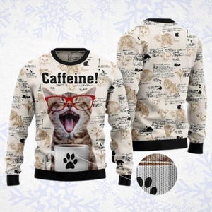 Puede incluir: Un suéter de manga larga con base color crema y un patrón repetitivo de gatos y tazas de café. El frente muestra un gato grande con gafas rojas, bostezando detrás de una taza blanca con una huella de pata negra y el texto Caffeine! en negro.