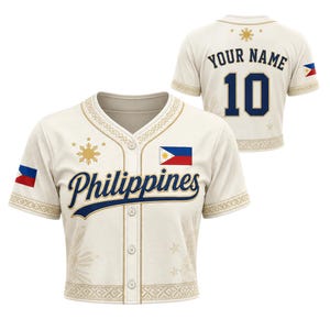 以下が含まれることがあります： クリーム色のボタンダウン野球用ジャージ。青い筆記体でPhilippinesの文字、フィリピン国旗のワッペン、金色の太陽と星のアクセントが特徴。背面には青と金の縁取りでYOUR NAMEの文字と数字の10がデザインされている。