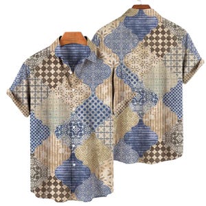 Può includere: Camicia a maniche corte con un design patchwork. La camicia presenta un mix di motivi geometrici e floreali nelle tonalità del blu, marrone e beige. La camicia è esposta su una gruccia di legno.