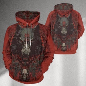 May include: Red hoodie with a detailed wolf design on the front and back. The wolf has a fierce expression with red eyes, surrounded by intricate patterns and a skull at the bottom. The hoodie has a drawstring and a hood.