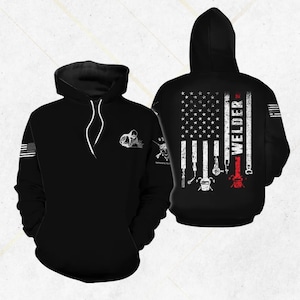 May include: Black hoodie featuring a white graphic of a welder on the front and an American flag design on the back. The back design includes the word "WELDER" and welding tools. The hoodie has a drawstring hood and a front pocket.