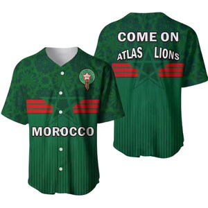 May include: Green baseball jersey with the word "MOROCCO" across the front. The jersey has a white collar and buttons. The back of the jersey says "COME ON ATLAS LIONS". The jersey has red stripes and a star design.