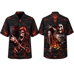 Puede incluir: Una camisa de manga corta con botones, fondo negro y patrón de lava roja. La parte delantera muestra una figura esquelética sosteniendo un cráneo, mientras que la parte trasera muestra un esqueleto emergiendo de un desgarro en la tela entre llamas.