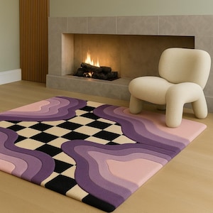 May include: A colorful area rug with a unique design featuring wavy lines in shades of purple, pink, and black and white checkerboard pattern. A cream-colored chair sits on the rug near a fireplace.
