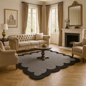 May include: A living room scene featuring a tufted beige sofa, two armchairs, and a round wooden coffee table. A gray rug with a black scalloped border sits on a herringbone wood floor. The room has large windows and a fireplace.