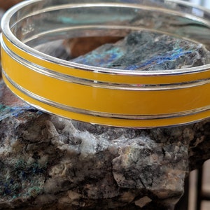 May include: A silver bangle bracelet with a double band of yellow enamel.