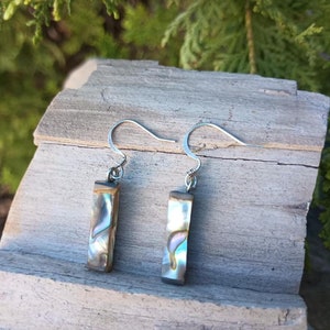 May include: A pair of silver dangle earrings with iridescent abalone shell rectangular pendants.