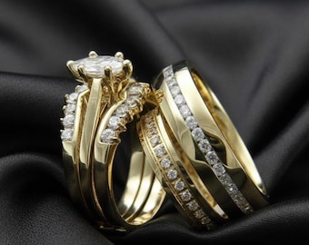 May include: A pair of gold wedding rings with diamond accents. The engagement ring features a large, oval-cut diamond center stone, and the wedding band is adorned with smaller diamonds. The rings rest on a black satin surface.