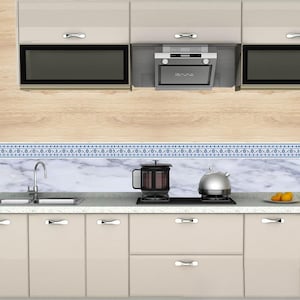 May include: A modern kitchen with light beige cabinets, stainless steel appliances, and a marble backsplash. A French press and a silver kettle sit on the stovetop. The kitchen features a microwave, range hood, and a sink.