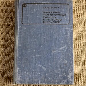 Peut inclure: Un livre bleu vintage avec du texte dans un cadre rectangulaire. La couverture du livre est décolorée et usée, avec des signes visibles de vieillissement. Le fond est un tissu texturé, beige.