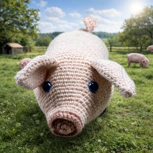 Könnte beinhalten: Ein handgehäkeltes, hellrosa Schwein mit großen blauen Augen, Schlappohren und einem eingerollten Schwanz. Das Schwein befindet sich auf grünem Gras, im Hintergrund grasen weitere Schweine unter einem strahlend blauen Himmel. Ein charmantes, skurriles Bauernhoftier.