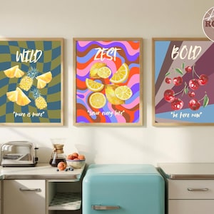 Puede incluir: Tres láminas enmarcadas con ilustraciones de frutas. Una presenta piñas y la palabra "WILD", otra limones y la palabra "ZEST", y la última cerezas con la palabra "BOLD". Cada lámina tiene una combinación de colores y texto únicos.