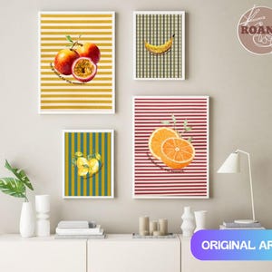 Puede incluir: Una colección de impresiones artísticas enmarcadas con ilustraciones de frutas. Las impresiones muestran un plátano, naranjas, manzanas y maracuyá sobre fondos a rayas y a cuadros. El texto "The grateful for this moment" está incluido en algunas impresiones. El arte está etiquetado como "ORIGINAL ART".