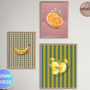 Puede incluir: Tres impresiones artísticas enmarcadas con ilustraciones de frutas. Un plátano se muestra sobre un fondo a cuadros verdes y blancos. Las naranjas se muestran sobre un fondo a rayas rojas y blancas. Los limones están sobre un fondo a rayas azules y amarillas.