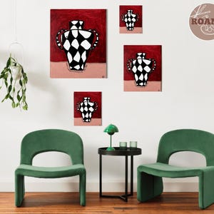 Puede incluir: Una colección de obras de arte enmarcadas con un diseño de jarrón a cuadros en blanco y negro sobre un fondo rojo. La obra de arte se exhibe en una pared blanca sobre dos sillas de terciopelo verde. También se ven una pequeña mesa auxiliar negra y una lámpara verde.