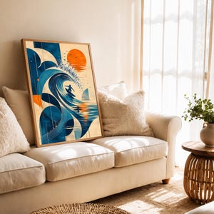Puede incluir: Una impresión de arte mural rectangular enmarcada que presenta una ilustración gráfica estilizada de un surfista montando una gran ola azul. La obra incluye un sol naranja brillante, formas geométricas y un fondo color crema con detalles en azul oscuro.