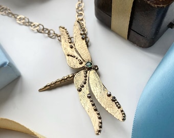 Darting gold dragonfly set with six diamonds and a fabulous Emerald, on a long, over-the-head, handmade solid gold chain.
