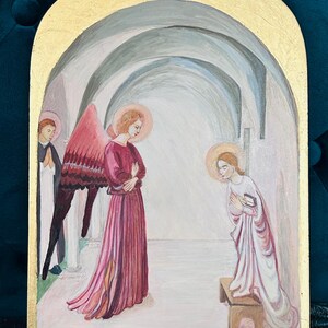 May include: An original painting depicting a religious scene. The artwork features three figures in a vaulted interior, with a gold-painted frame. The central figure is an angel with pink wings and a red dress. The other two figures are also wearing robes.