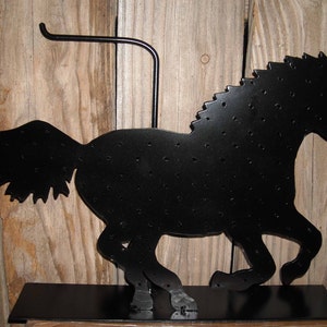 May include: Black metal horse silhouette earring holder with a stand and a hook on the top. The horse is covered in small holes for holding earrings.
