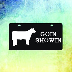 May include: Black and white silhouette of a cow on a black background with the text "GOIN SHOWIN" in white.