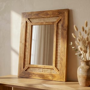 May include: A rectangular wall mirror featuring a natural brown wood frame with a visible grain pattern and an inner border of woven cane webbing. The mirror glass is clear and reflective, set within the wooden structure with mitered corners.