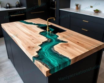 May include: A wooden kitchen island with a teal epoxy river design. The island features a light-colored wood surface with a teal epoxy resin river running through the center. A gold faucet is installed in the black sink. The island is supported by a black base.
