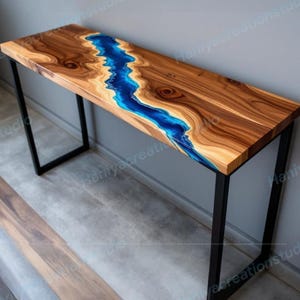 May include: A wooden console table with a live edge design and a blue resin river. The table has a rectangular top and black metal legs. The wood has a natural grain pattern. The table is approximately 48 inches long.