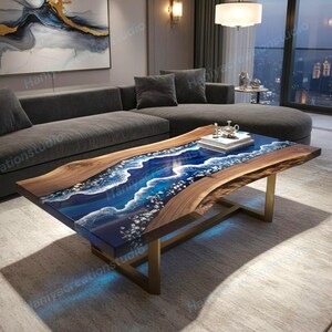 Op de afbeelding: Een unieke salontafel met een houten rand en een blauw hars midden, dat lijkt op oceaangolven. De tafel heeft een rechthoekige vorm met goudkleurige metalen poten. Een decoratief dienblad en boeken zijn bovenop geplaatst.