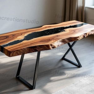 May include: A rectangular wooden table with a live edge and a black epoxy river down the center. The table has a natural wood grain finish and sits on black metal legs. The table is approximately 72 inches long.