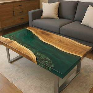 Puede incluir: Una mesa de centro rectangular con un diseño único. La mesa presenta un centro de resina epoxi verde oscuro con piedras incrustadas, enmarcado por bordes de madera natural. Descansa sobre una base de metal plateado, creando una estética moderna.